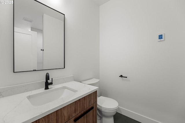 half bath featuring baseboards, toilet, vanity, and tile patterned flooring