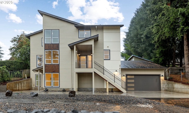 contemporary home featuring stairs, an attached garage, driveway, and fence