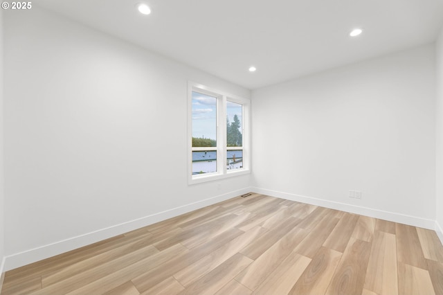 empty room with recessed lighting, light wood-type flooring, and baseboards