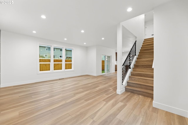 unfurnished living room featuring stairs, recessed lighting, baseboards, and light wood finished floors