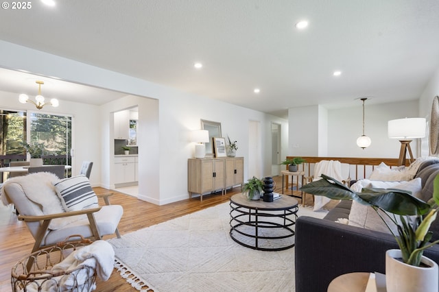 living room with a chandelier, light wood finished floors, baseboards, and recessed lighting