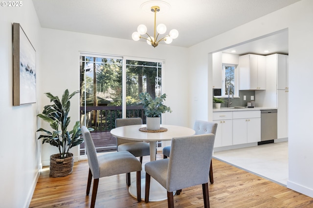 dining room with light wood-type flooring, plenty of natural light, baseboards, and an inviting chandelier