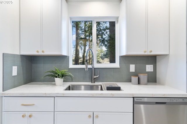 kitchen featuring light stone counters, white cabinets, dishwasher, and a sink