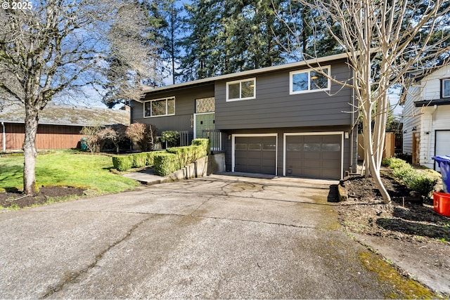 split foyer home with driveway, a front lawn, an attached garage, and fence