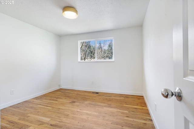 unfurnished room featuring visible vents, baseboards, a textured ceiling, and light wood finished floors