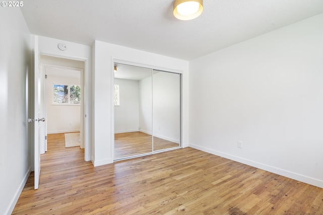 unfurnished bedroom with light wood finished floors, a closet, and baseboards