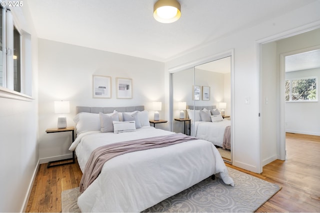 bedroom featuring light wood-style flooring, baseboards, and a closet