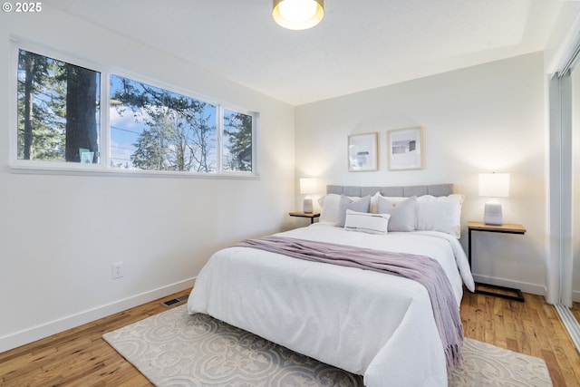 bedroom with multiple windows, visible vents, and light wood-style floors