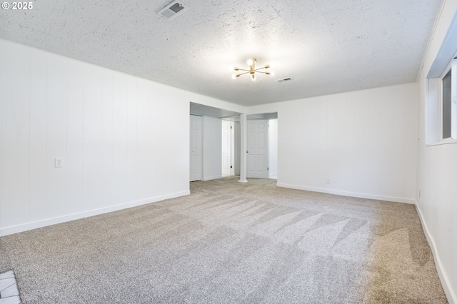 unfurnished room featuring a textured ceiling, carpet floors, visible vents, and baseboards