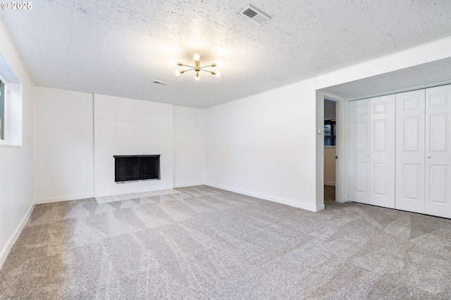 unfurnished living room with carpet floors, a large fireplace, visible vents, and a textured ceiling