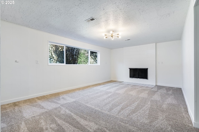 unfurnished living room featuring a large fireplace, a textured ceiling, carpet flooring, and visible vents