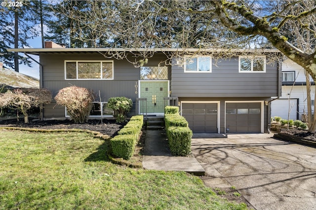 split foyer home featuring a garage, a front yard, driveway, and a chimney