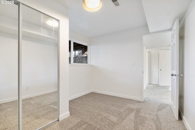 unfurnished bedroom featuring visible vents, a closet, baseboards, and carpet flooring