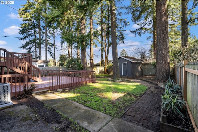 view of yard with an outbuilding, a deck, a fenced backyard, central AC, and a storage unit