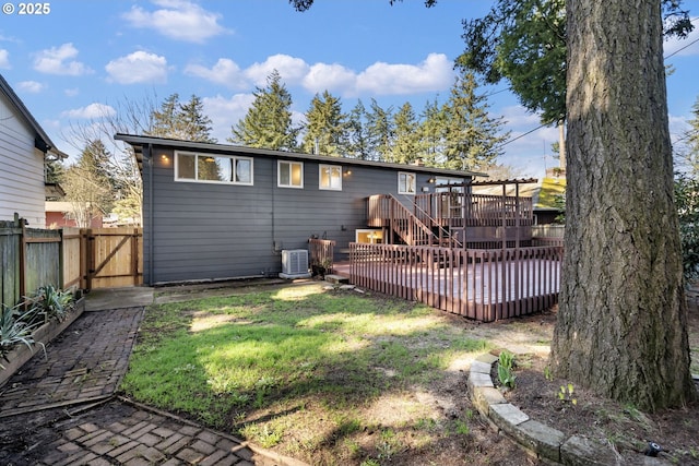 back of house featuring a fenced backyard, a gate, a deck, cooling unit, and a yard