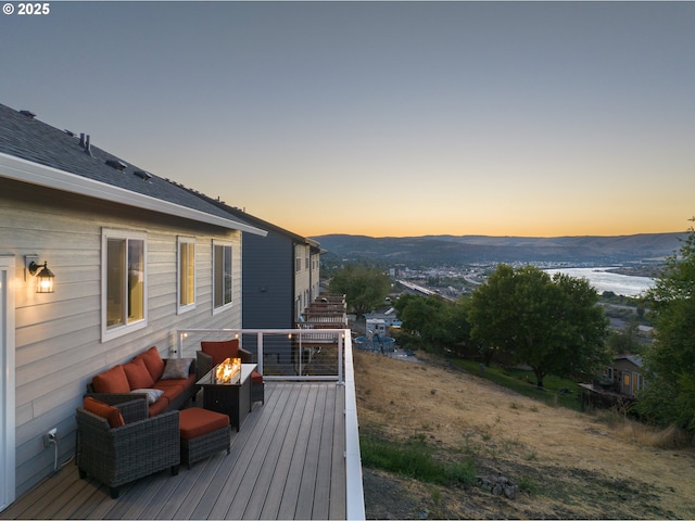 deck at dusk featuring a mountain view and an outdoor living space with a fire pit