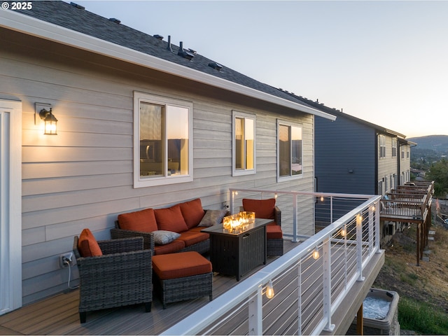 deck at dusk with an outdoor living space with a fire pit