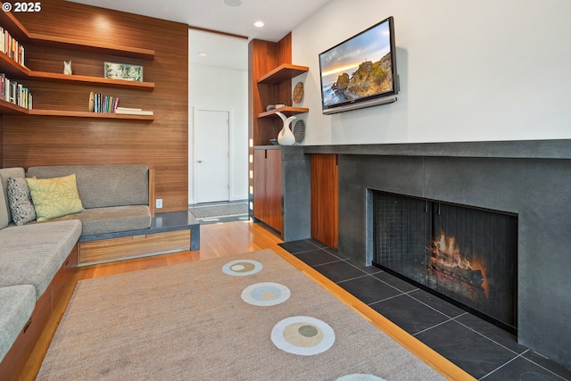 living room with a tiled fireplace, dark hardwood / wood-style floors, and built in shelves