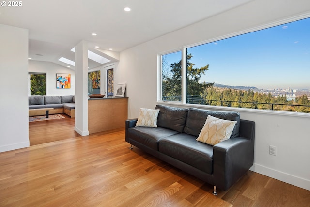 living room with plenty of natural light, lofted ceiling, and light wood-type flooring