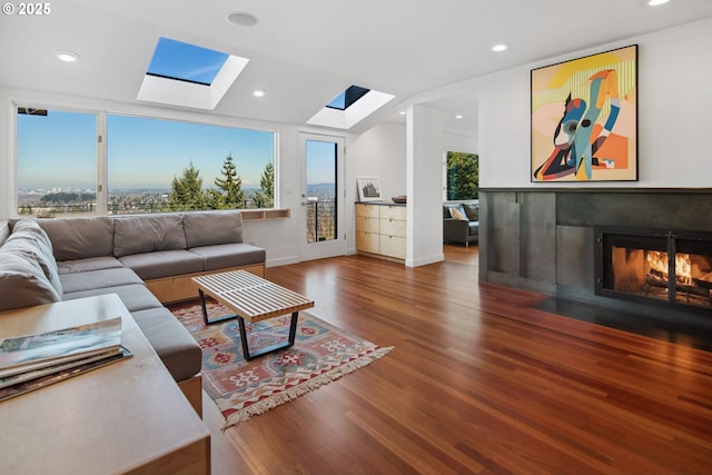 living room with vaulted ceiling with skylight, hardwood / wood-style floors, and a wealth of natural light