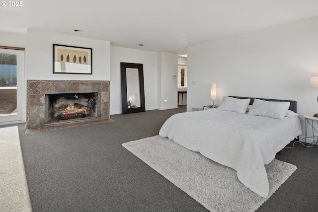 bedroom featuring a tile fireplace and dark colored carpet