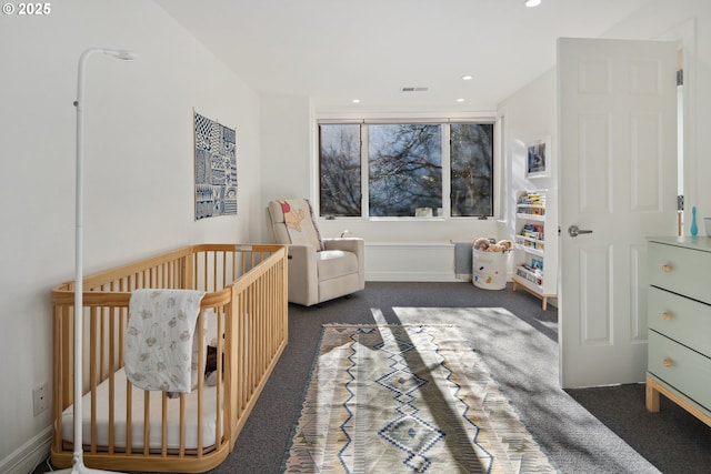 bedroom with a nursery area and dark colored carpet