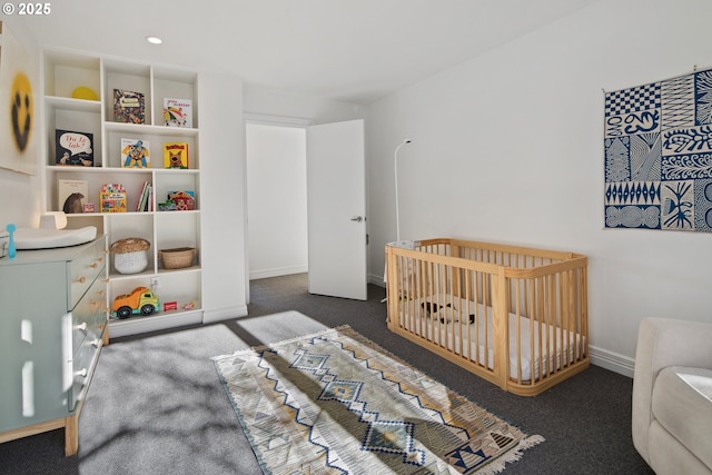 bedroom with a nursery area and dark colored carpet