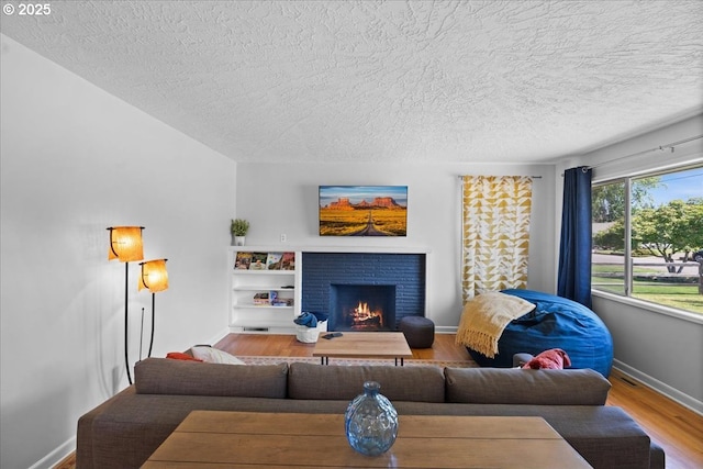 1637 Camino Dr, Forest Grove, OR 97116 - living room featuring a textured ceiling, wood finished floors, a brick fireplace, and baseboards