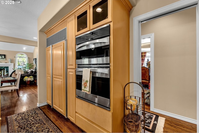 3420 SE 144th Ct, Vancouver, WA 98683 - kitchen featuring stainless steel double oven, dark wood-style flooring, glass insert cabinets, baseboards, and light brown cabinets