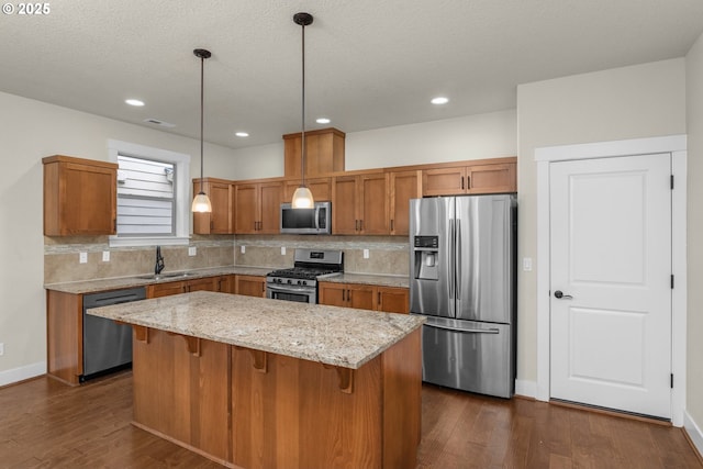 kitchen with appliances with stainless steel finishes, pendant lighting, light stone counters, and tasteful backsplash