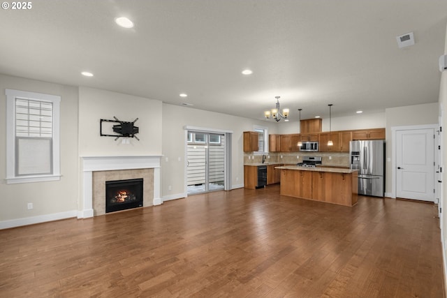 kitchen featuring pendant lighting, a center island, dark wood-type flooring, stainless steel appliances, and a tile fireplace