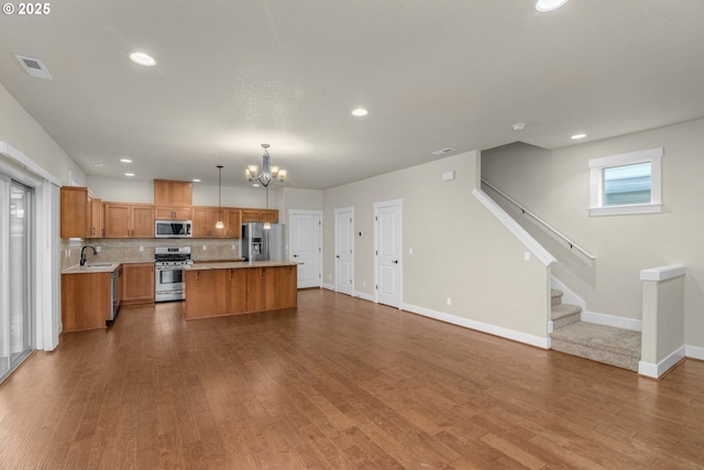 kitchen featuring a center island, stainless steel appliances, sink, hanging light fixtures, and a chandelier