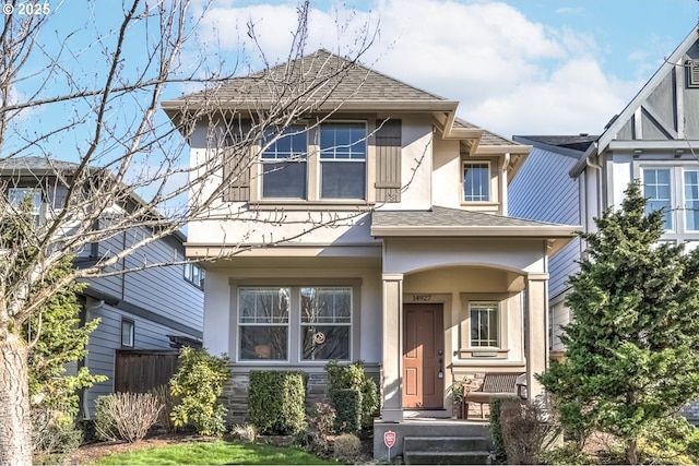 view of front of home with roof with shingles, fence, and stucco siding