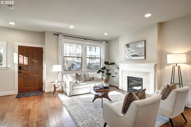 living room with recessed lighting, a brick fireplace, baseboards, and wood finished floors