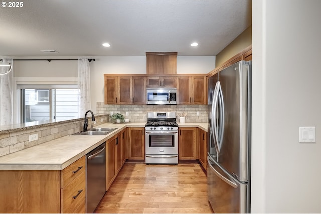 kitchen with appliances with stainless steel finishes, backsplash, a sink, and light countertops