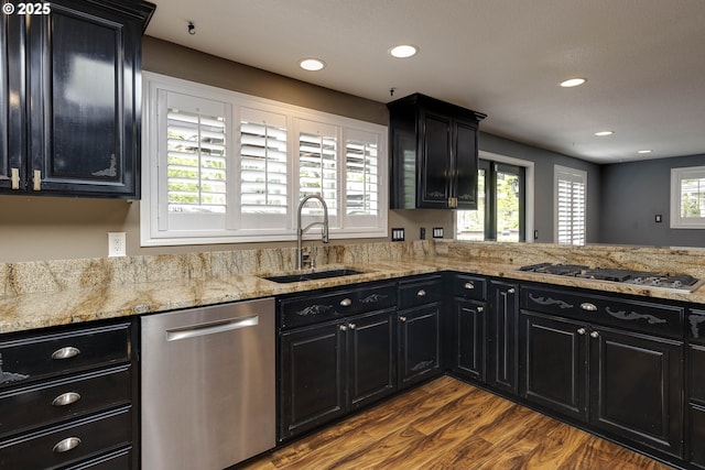 kitchen with dark cabinets, a sink, appliances with stainless steel finishes, and a wealth of natural light