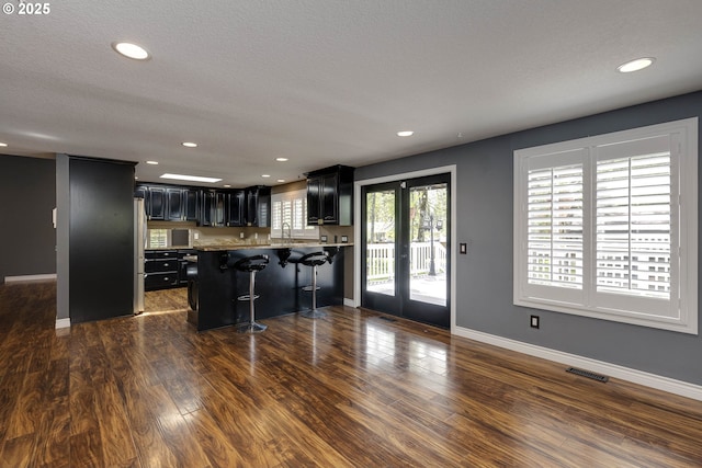 kitchen featuring dark cabinetry, recessed lighting, visible vents, and a kitchen bar