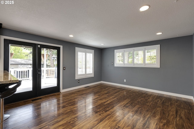 interior space with a textured ceiling, dark wood finished floors, recessed lighting, baseboards, and visible vents