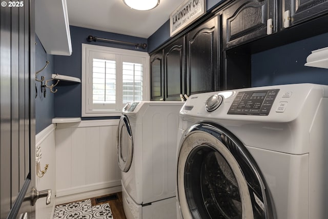 laundry area with visible vents, wainscoting, washing machine and dryer, wood finished floors, and cabinet space