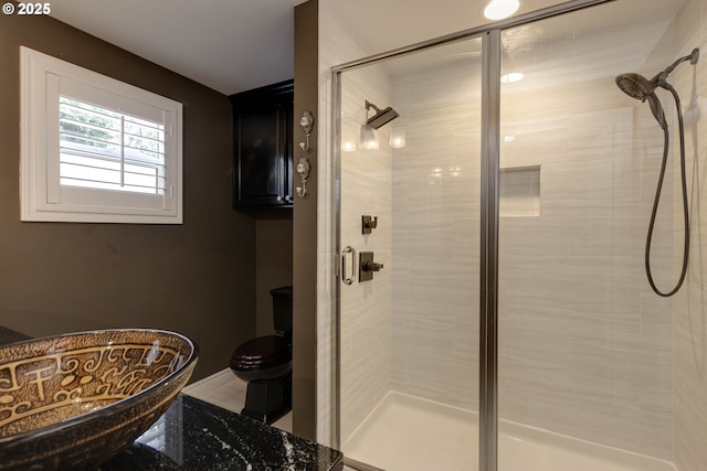 bathroom featuring baseboards, a stall shower, and toilet