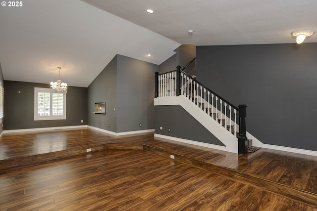 unfurnished living room with a chandelier, wood finished floors, and vaulted ceiling