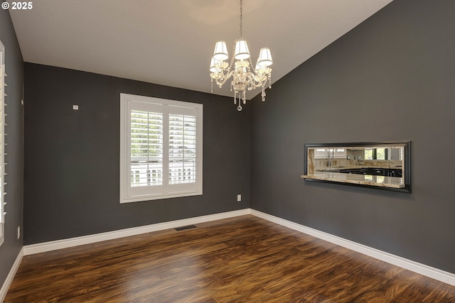 unfurnished room with visible vents, baseboards, wood finished floors, and a notable chandelier