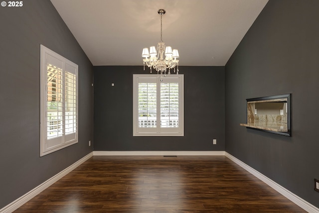 spare room with baseboards, vaulted ceiling, wood finished floors, and a notable chandelier