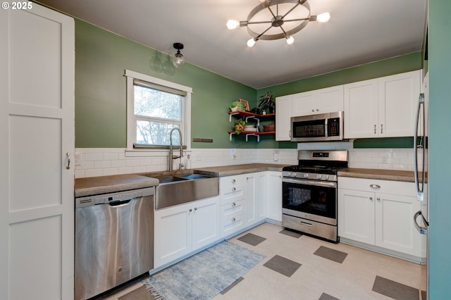 kitchen with white cabinetry, stainless steel appliances, sink, and decorative backsplash