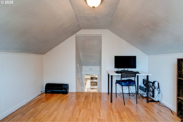 office space featuring lofted ceiling, hardwood / wood-style flooring, and a textured ceiling