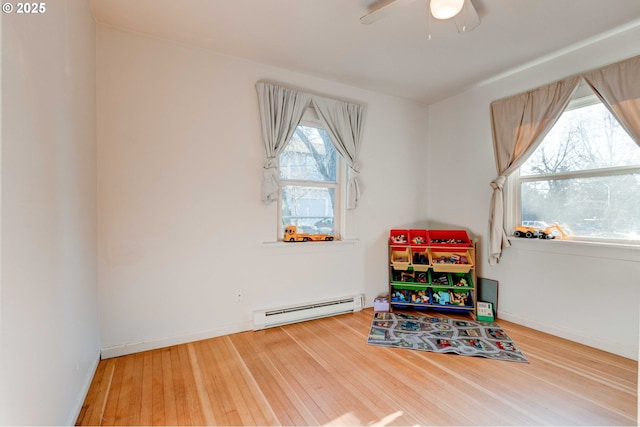 playroom featuring a baseboard heating unit, hardwood / wood-style flooring, and ceiling fan