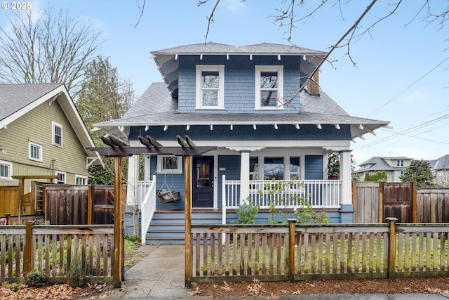 view of front of home with fence private yard, covered porch, and roof with shingles