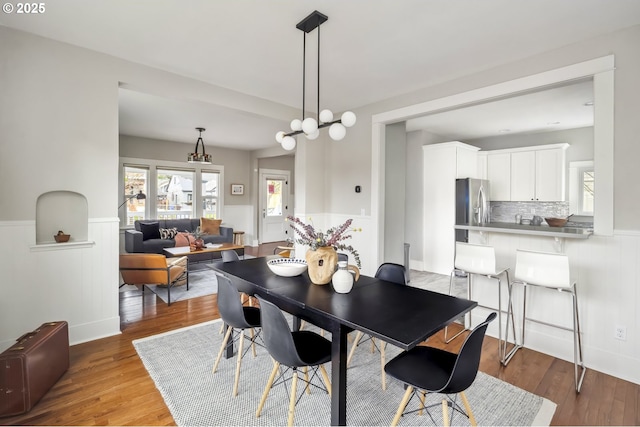 dining space featuring a wainscoted wall and wood finished floors