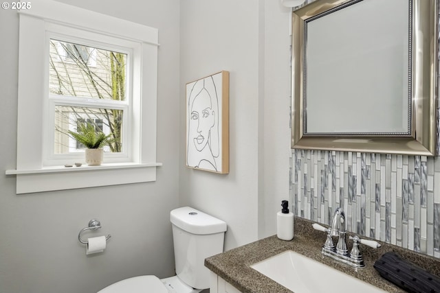 bathroom featuring vanity, toilet, and backsplash