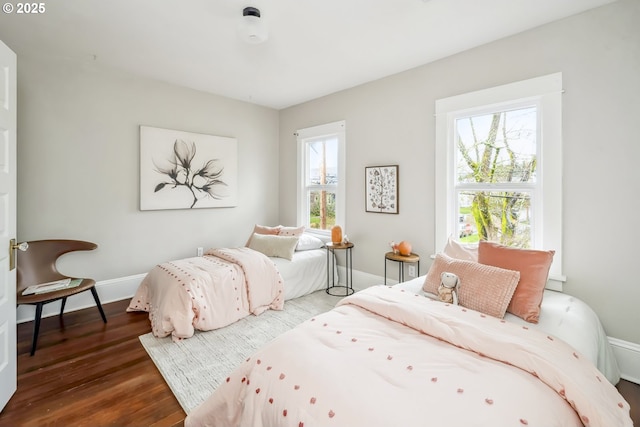 bedroom with multiple windows, wood finished floors, and baseboards